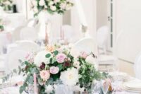 a delicate and refined floral wedding centerpiece with pink, white and burgundy blooms and greenery is ideal for a garden wedding