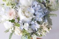 a delicate and textural wedding bouquet of white peonies, blue hydrangeas, blush roses, some fillers and greenery