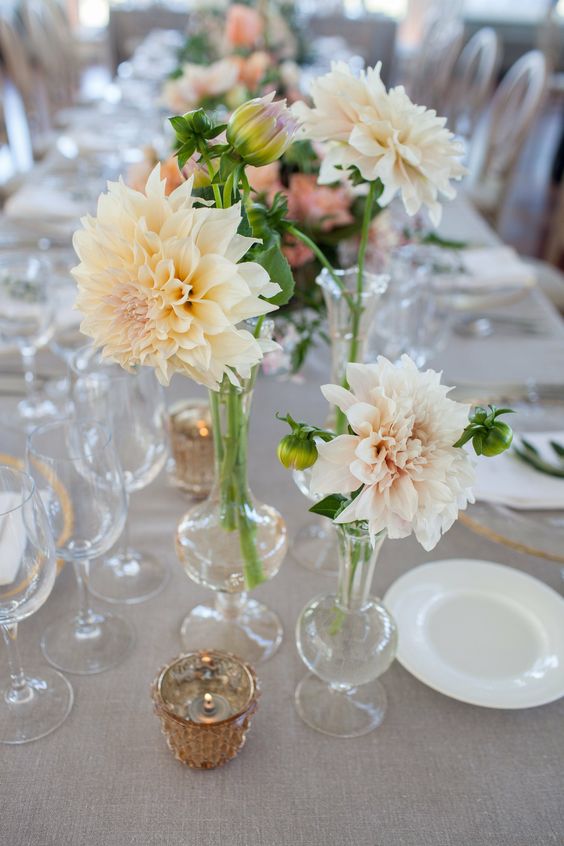 a delicate neutral cluster wedding centerpiece of clear vases, neutral dahlias and a candle is a lovely idea for a spring or summer wedding