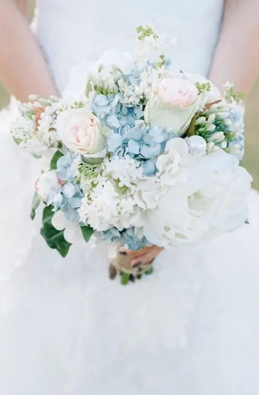 a delicate wedding bouquet featuring blue hydrangeas, ligth pink roses, lush white peonies is a beautiful idea for a summer wedding