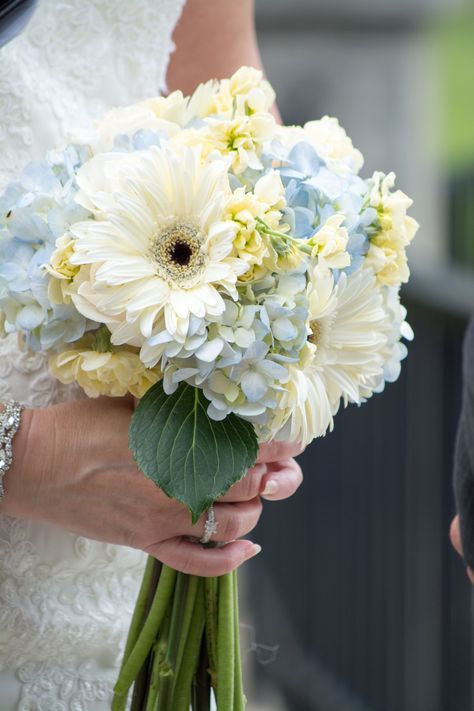 a delicate wedding bouquet of blue hydrangeas, white gerberas and some leaves is a simple and subtle arrangement for a spring or summer wedding
