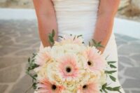 a delicate wedding bouquet of blush gerberas and white roses, greenery and twigs shaped as a ball is a cool and fun idea