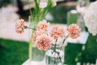 a delicate wedding centerpiece of a clear vase with blush carnations is a lovely idea for a modern wedding