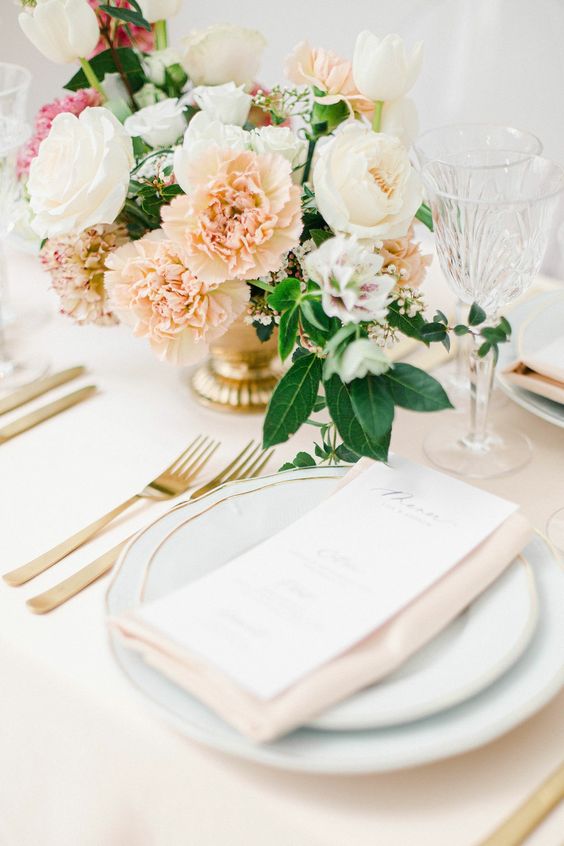 a delicate wedding centerpiece of white peonies and tulips, blush carnations and foliage is a cool idea for spring weddings