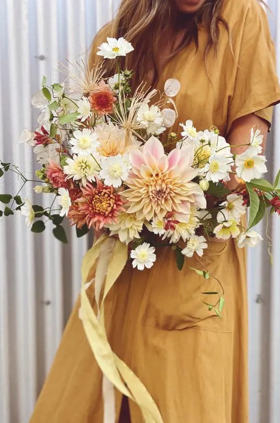 a dreamy fall wedding bouquet of white blooms and blush and pink dahlias, greenery and yellow ribbon is all cool