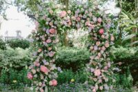 a dreamy pastel wedding arch decorated with greenery, pink peonies, blush roses and lilac blooms is a lovely idea for spring