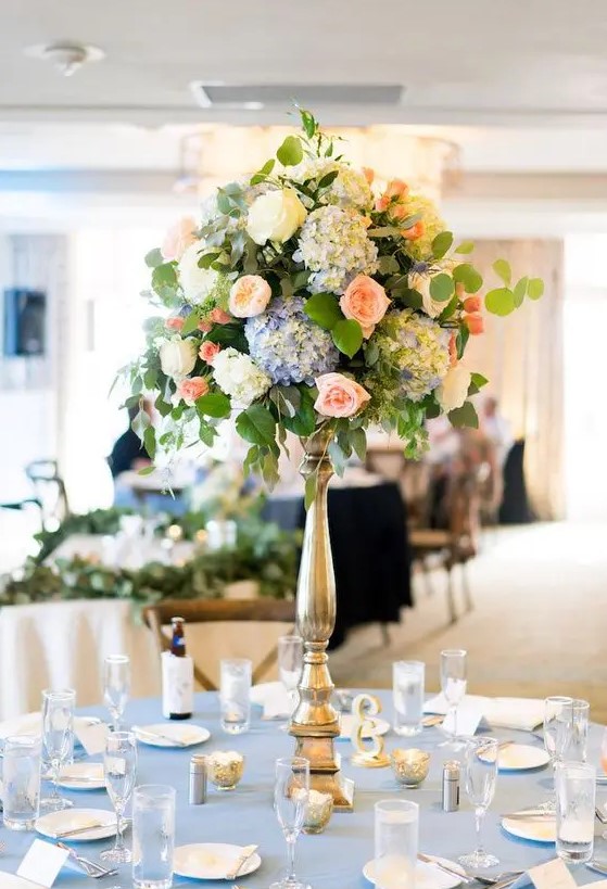 a dreamy tall wedding centerpiece of white, blue and peachy pink blooms and greenery is a lovely and cool idea for a secret garden wedding