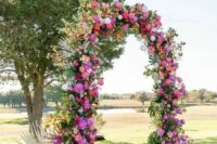 a fabulous wedding arch with peachy, orange and hot pink blooms, greenery and frinds is a lovely idea for a bright wedding