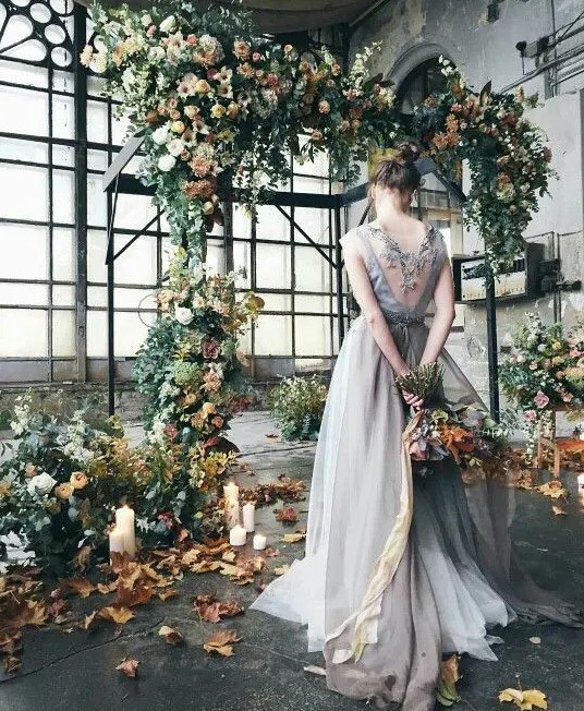 a fall-inspired floral arch in subtle pastel tones, with greenery and fall leaves placed inside