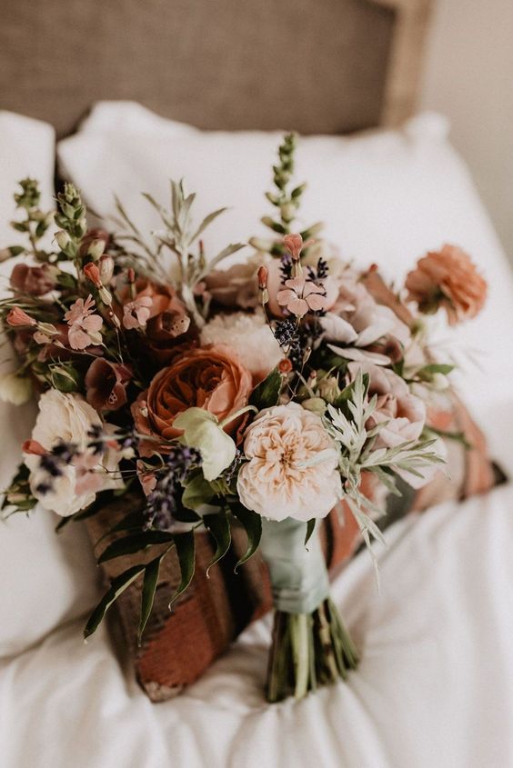 a fall wedding bouquet of blush carnations and some coffee-colored ranunculus, greenery, berries and textured touches