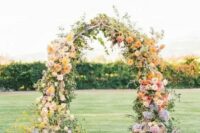 a fantastic bright wedding arch with yellow, pink, blue and lilac blooms and greenery is amazing for a bright wedding