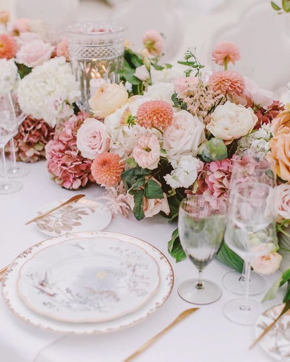 a fantastic lush wedding centerpiece of pink roses and hydrangeas, roses and dahlias and candle holders