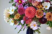 a gorgeous colorful wedding bouquet of white, rust, orange, fuchsia, pink blooms and greenery and long navy ribbons for a colorful wedding