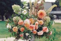 a gorgeous fall wedding arrangement with orange dahlias, pink roses, white blooms, greenery and green hydrangeas