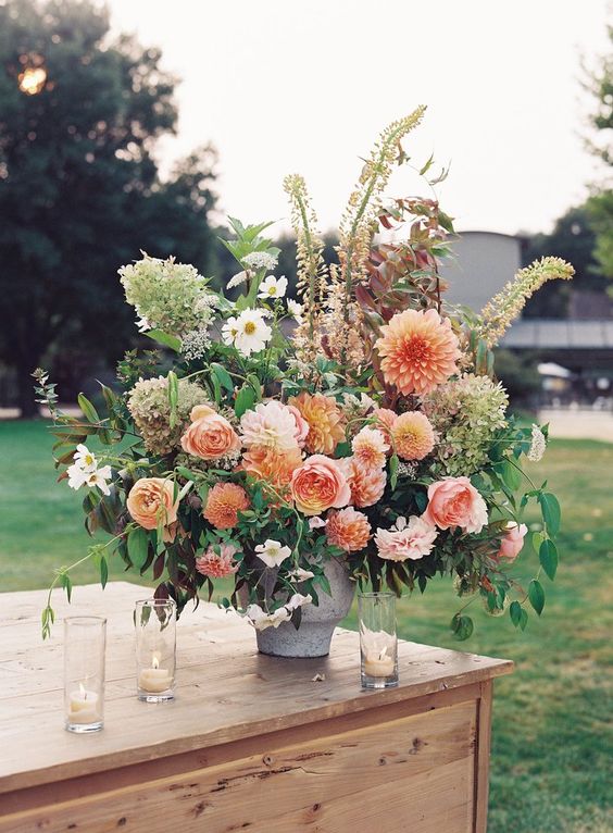 a gorgeous fall wedding arrangement with orange dahlias, pink roses, white blooms, greenery and green hydrangeas