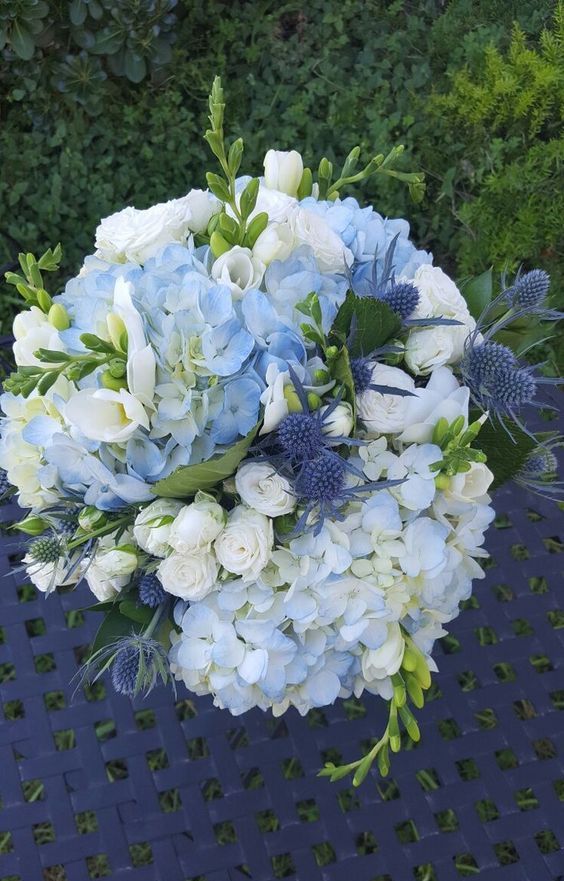 a light blue wedding bouquet of hydrangeas, garden roses, thistles and greenery is a cool and chic idea for spring and summer