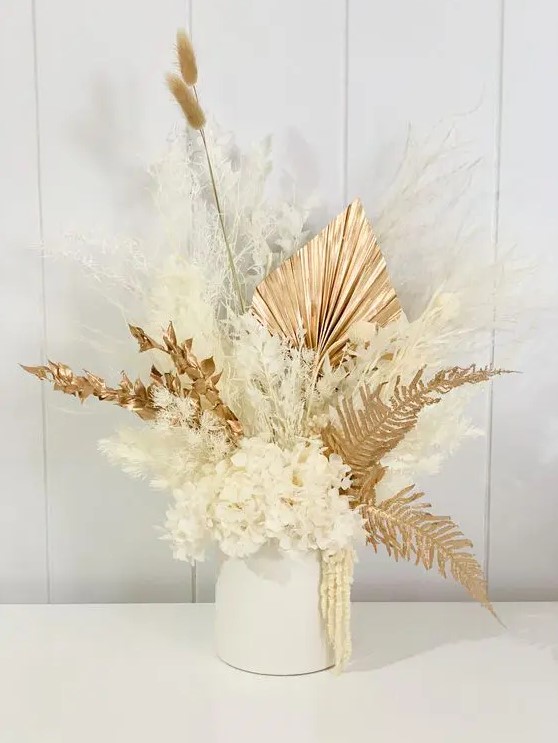 a lovely dried flower wedding centerpiece of gilded leaves, fronds, bunny tails, white blooms and white grasses is a gorgeous idea