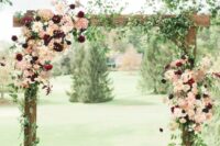 a lovely fall wedding arch with greenery, blush and burgundy dahlias and roses is a stylish rustic wedding idea