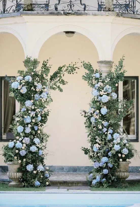 a lovely hydrangea wedding altar created in a real wedding arch, with greenery and light blue hydrangeas is a delicate and chic idea