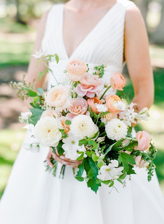 a lovely summer wedding bouquet of white dahlias, peachy and coral ranunculus, greenery and fillers is chic