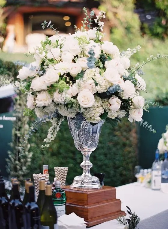 a lovely tall wedding centerpiece of a crystal vase, white blooms and lots of greenery and eucalyptus is a chic idea