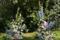 a lovely wedding altar with white and pink hydrangeas, blue deliphinium and some greenery for a summer wedding