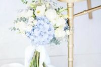a lovely wedding bouquet of blue hydrangeas and white peonies and roses, eucalyptus and light blue ribbons