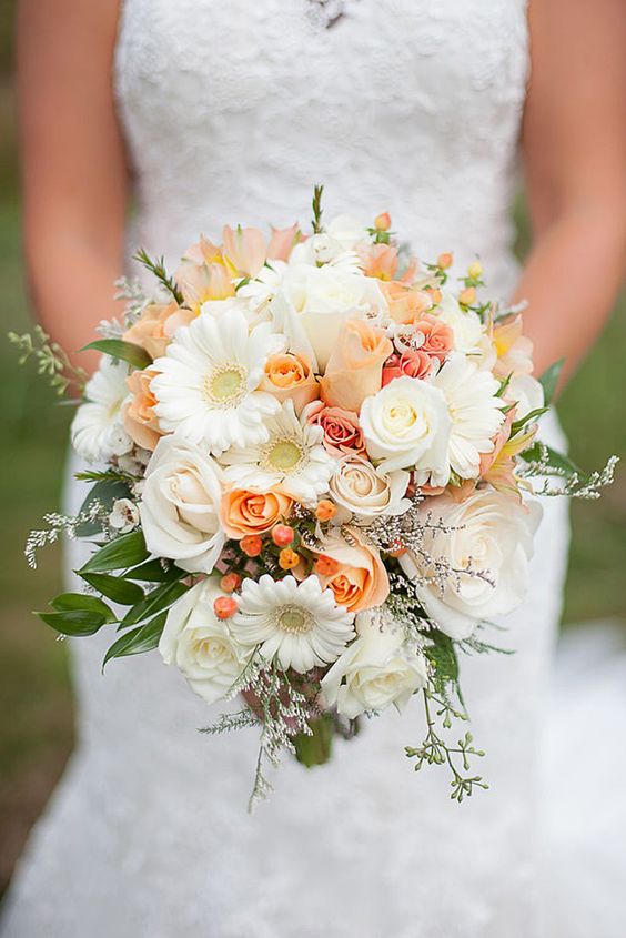 a lovely wedding bouquet of orange roses, berries, white roses and gerberas, some leaves and fillers for a spring or summer wedding