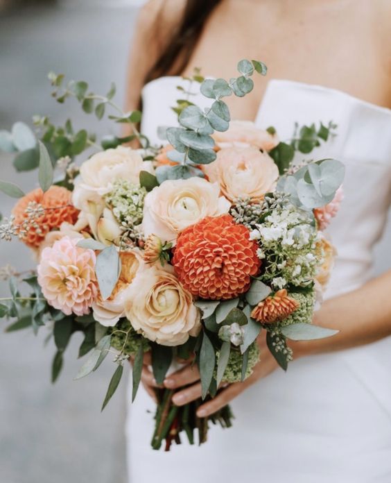 a lovely wedding bouquet of ranunculus, blush and orange dahlias, two types of eucalyptus is a gorgeous fall solution