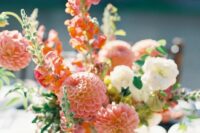 a lovely wedding centerpiece of pink dahlias, white roses and a bit of foliage for a coral summer wedding