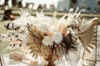 a lush and lovely wedding centerpiece of white fresh and dried blooms, fronds, grasses, cotton and bunny tails is a pretty idea