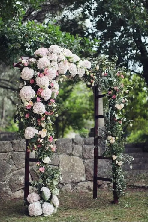 a lush wedding arch covered with lush florals on one side and with greenery for a spring feeling