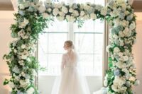 a lush wedding arch decorated with white and blue hydrangeas and greenery is an elegant and traditional idea for spring and summer