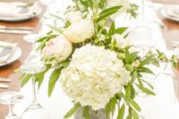 a lush white hydrangea wedding centerpiece with blush roses and greenery and candles around is a cool and chic idea