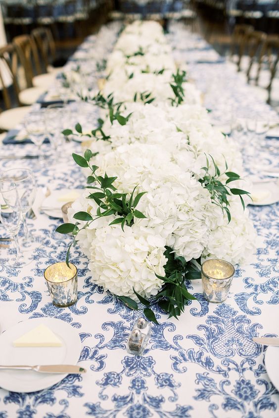 a lush white hydrangea wedding table runner with greenery and candles is a cool idea for a rustic wedding