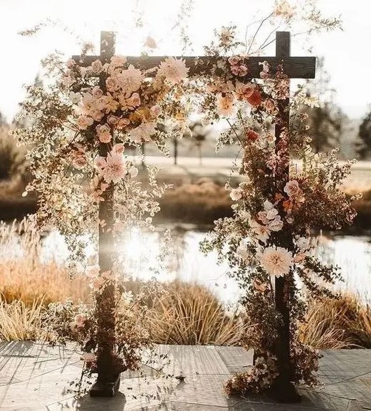 a luxurious boho fall wedding arch decorated with blush, rust and peachy blooms, euclayptus, dried leaves looks fantastic