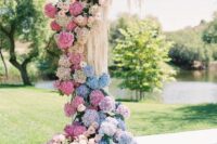 a pastel wedding arch done with white and blush roses and blue, pink and blush hydrangeas plus some cascading elements