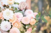 a pastel wedding bouquet of pink and orange dahlias, lilac and orange blooms and ranunculus, greenery for a delicate pastel summer wedding