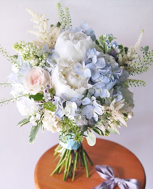 a pastel wedding bouquet of white peonies, blush roses, blue hydrangeas, greenery and astilbe is a lovely idea for spring or summer