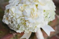 a pretty wedding bouquet of white hydrangeas and roses plus a white ribbon wrap is a stylish and catchy idea for spring or summer