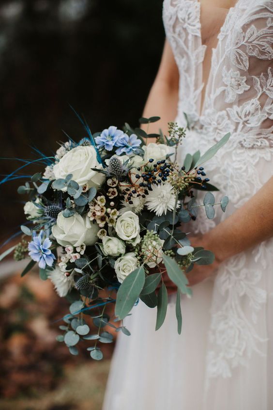 a pretty wedding bouquet of white roses and waxflower, berries, greenery and twigs is a cool and chic arrangement for spring or summer