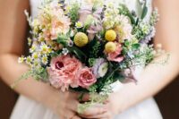 a pretty wildflower wedding bouquet of blush roses, carnations, billy balls, grasses, lavender and greenery