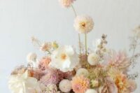 a refined and chic pastel and neutral wedding centerpiece of white and blush dahlias, white peonies, some mauve fillers