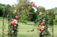 a refined vintage wedding arch made of a vintage gate, with greenery, neutral, peachy and pink blooms is chic