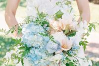 a refined wedding bouquet of blue hydrangeas, peachy and blush blooms, greenery and twigs is a lovely idea for spring
