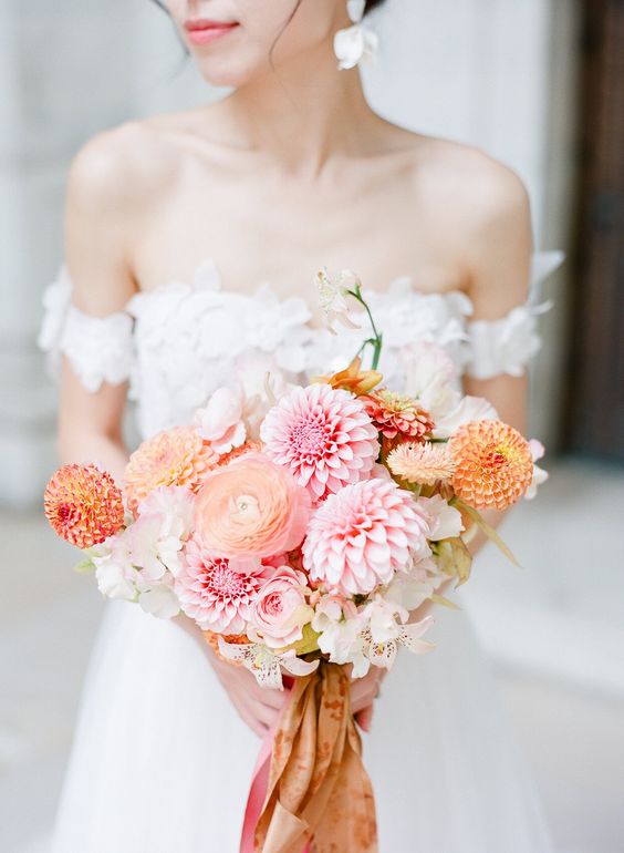 a refined wedding bouquet of pink and orange dahlias, neutral blooms and peachy ranunculus plus ribbons