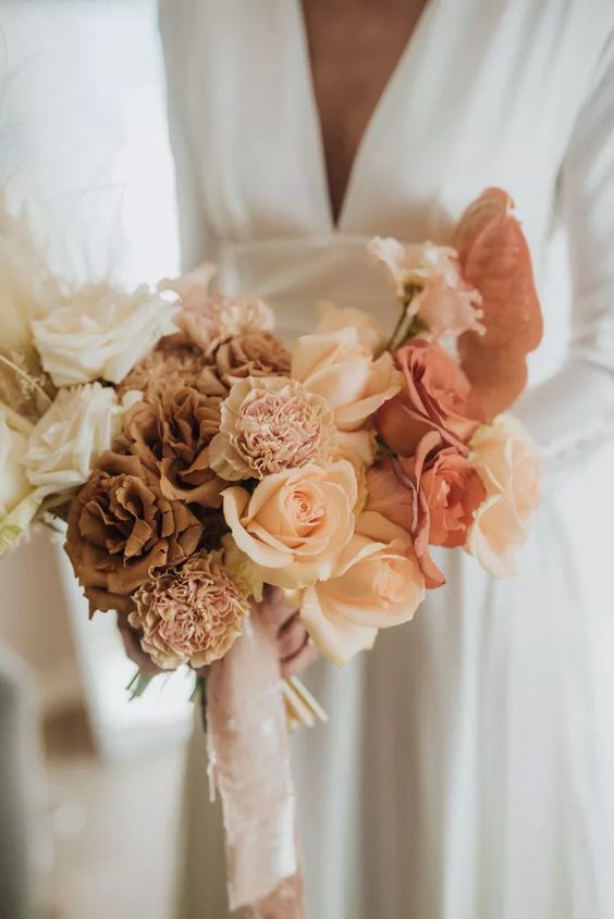 a refined wedding bouquet of white, coffee-colored and rust and peachy roses, blush carnations and neutral ribbons is fantastic