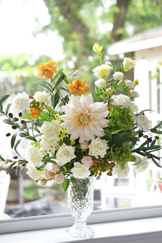a refined wedding centerpiece of white dahlias and roses, yellow carnations, greenery and berries is a lovely idea for summer