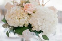 a refined wedding centerpiece of white hydrangeas, blush roses and greenery is a cool idea for spring and summer