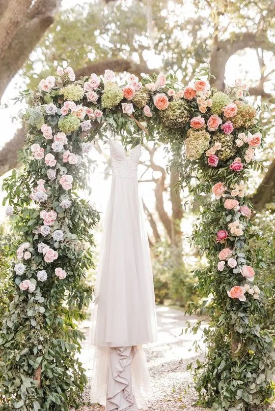 a romantic garden wedding arch with greenery, pink, peachy and green blooms is a very beautiful and classic idea